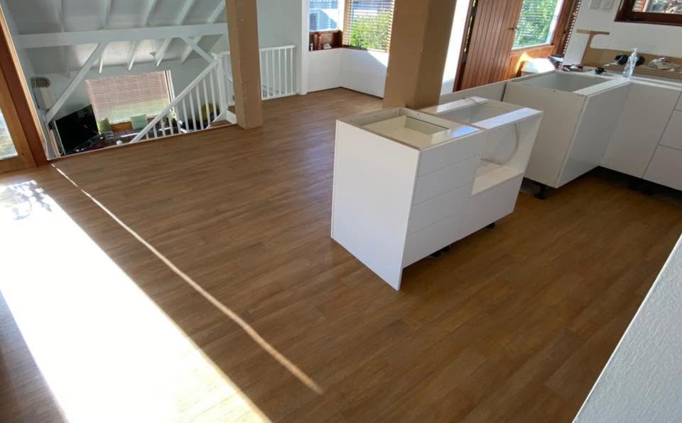 Sunlit open-plan living room with wood grain vinyl plank flooring laid by J & R Flooring